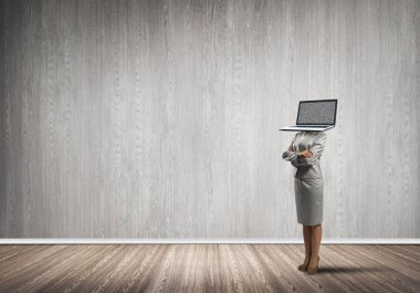 Arka plan üzerinde duran gri duvar ile boş oda içinde iş kadını kıyafetli dizüstü bilgisayar kafasına silah tutmak yerine geçti.