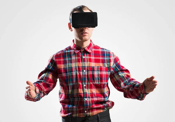 Young man in checked shirt wearing virtual helmet against gray background