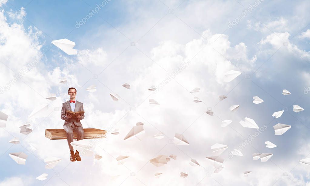 Funny man in red glasses and suit sitting on book and paper planes flying around