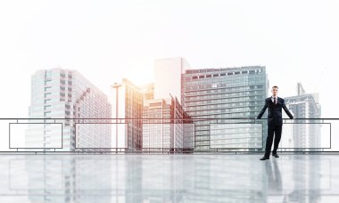 Balkonda takım elbiseli genç bir işadamı sabah şehir manzarasına karşı.