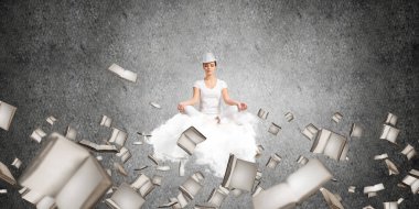Kadın beyaz giyim gözler tutmak kapalı ve seyir üzerinde uçan bulut kitaplar ile gri karanlık duvar arka plan üzerinde uçan arasında meditasyon sırasında konsantre.
