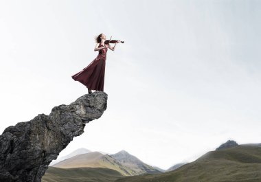 Keman ayakta rock üst kısmında oynayan genç çekici kız