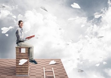 Elinde kırmızı kitap ile ev rahat oturan genç adam