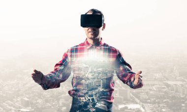 Sanal gerçeklik kulaklığı olan genç bir adam ya da şehrin arka planında 3 boyutlu gözlüklü.