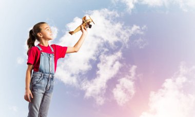 Elinde retro uçak modeliyle tulumlu şirin bir kız çocuğu.