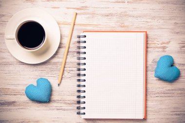 Kahve fincanı not defteri kalem ve ahşap yüzeyde iki kalp