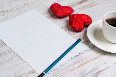 Kahve fincanı not defteri kalem ve ahşap yüzeyde iki kırmızı kalp