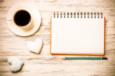Kahve fincanı not defteri kalem ve ahşap yüzeyde iki kalp