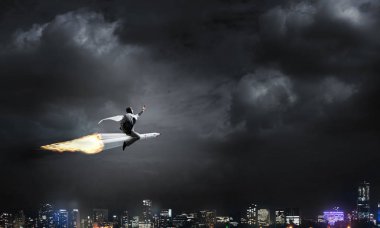 Arka plan üzerinde gece cityscape ve mavi gökyüzü ile roket üzerinde uçan takım elbiseli genç işadamı kavramsal görüntü.