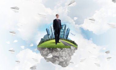 Mavi gök yeşil yüzen ada üzerinde duran zarif emin iş adamı