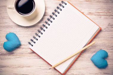 Kahve fincanı not defteri kalem ve ahşap yüzeyde iki kalp