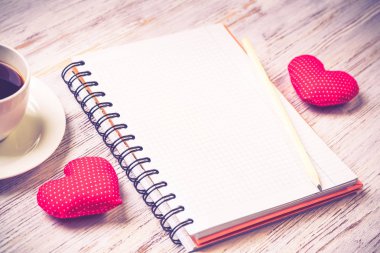 Kahve fincanı not defteri kalem ve ahşap yüzeyde iki kırmızı kalp