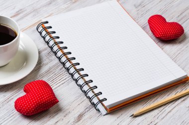 Kahve fincanı not defteri kalem ve ahşap yüzeyde iki kırmızı kalp