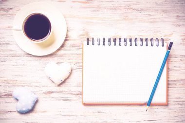 Kahve fincanı not defteri kalem ve ahşap yüzeyde iki kalp