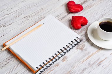 Kahve fincanı not defteri kalem ve ahşap yüzeyde iki kırmızı kalp