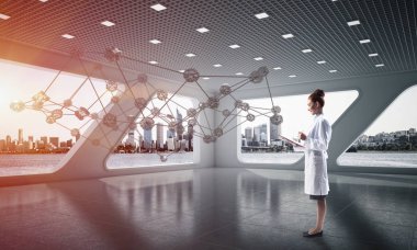 Beyaz hastane binası içinde ayakta iken sosyal ağ yapısını okuyan beyaz elbise emin kadın doktor yatay çekim. Medikal Sanayi konsepti