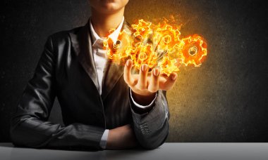 İşadamı ile arka plan üzerinde koyu duvar elinde sunan yanan cogwheels yapısı uygun.