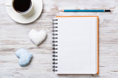 Kahve fincanı not defteri kalem ve ahşap yüzeyde iki kalp