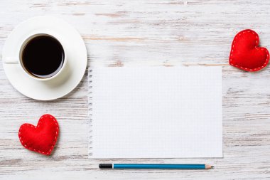 Kahve fincanı not defteri kalem ve ahşap yüzeyde iki kırmızı kalp