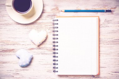 Kahve fincanı not defteri kalem ve ahşap yüzeyde iki kalp