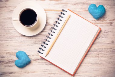 Kahve fincanı not defteri kalem ve ahşap yüzeyde iki kalp