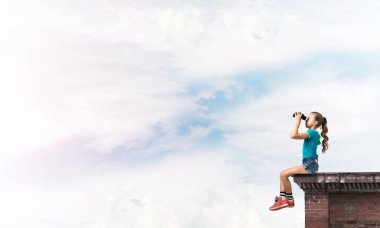 Dürbünle bakan, okul çağındaki sevimli kız çatıyı inşa ediyor.