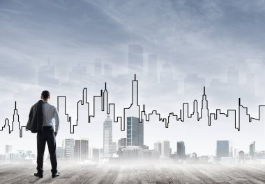 İşadamı arkasını dönüp modern iş merkezinin siluetine bakıyor.