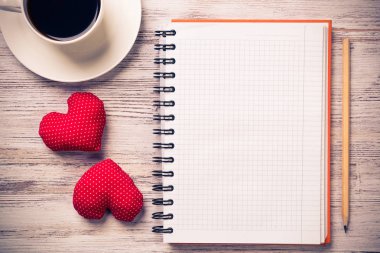 Kahve fincanı not defteri kalem ve ahşap yüzeyde iki kırmızı kalp