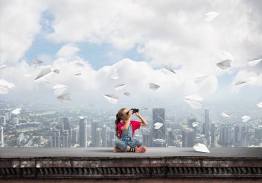 Dürbünle bakan, okul çağındaki sevimli kız çatıyı inşa ediyor.