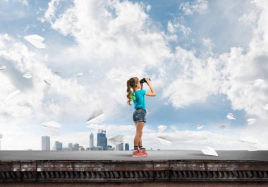 Dürbünle bakan, okul çağındaki sevimli kız çatıyı inşa ediyor.