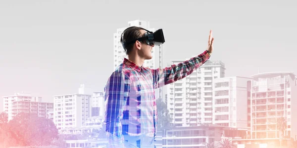 Young man with virtual reality headset or 3d glasses over cityscape background