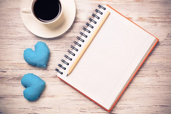 Kahve fincanı not defteri kalem ve ahşap yüzeyde iki kalp