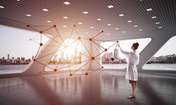 Beyaz hastane ofisi içinde ayakta iken sosyal ağ yapısı ile çalışan beyaz Tıbbi üniforma genç kadın doktorun yatay çekim. Medikal Sanayi