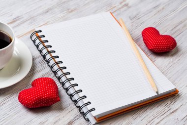 Kahve fincanı not defteri kalem ve ahşap yüzeyde iki kırmızı kalp