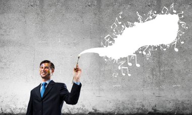 Arka planda gri koyu duvara karşı beyaz müzikal sıçrama ile siyah takım elbise ayakta başarılı ve güvenilir işadamı kavramsal görüntü.