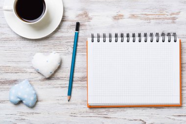 Kahve fincanı not defteri kalem ve ahşap yüzeyde iki kalp