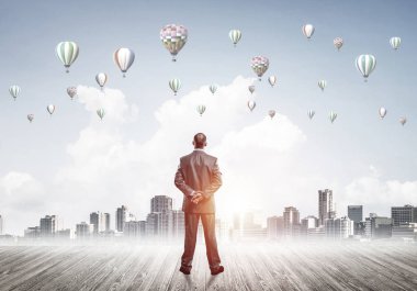 Arka ayakta ve havada uçan aerostats bakarak bir işadamı