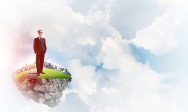 Mavi gök yeşil yüzen ada üzerinde duran zarif emin iş adamı