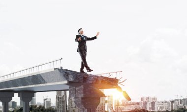 Yürüyüş işadamı gizli tehditler ve riskler sembolü olarak kocaman bir boşluk ile beton köprü üzerinde gözü kapalı. Cityscape ve arka plan üzerinde güneş ışığı. 3D render.