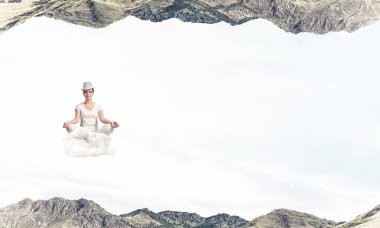 Genç kadın gözleri koruma kapalı ve seyir bulut doğa dünyalar arasında havada meditasyon sırasında konsantre.