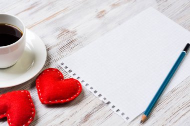 Kahve fincanı not defteri kalem ve ahşap yüzeyde iki kırmızı kalp
