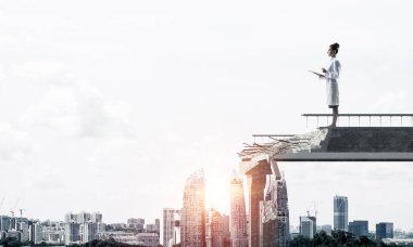 Arkaplanda şehir manzarası olan kırık bir köprünün üzerinde dururken elinde defteri tutan genç bir kadın doktorun kavramsal görüntüsü. Tıp endüstrisi konsepti