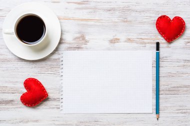 Kahve fincanı not defteri kalem ve ahşap yüzeyde iki kırmızı kalp