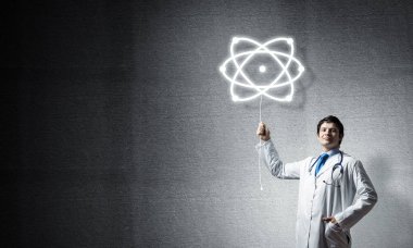 Başarılı ve beyaz üniformalı genç bir doktor, arka planda gri beton duvara karşı dururken moleküler yapıyla etkileşime giriyor..