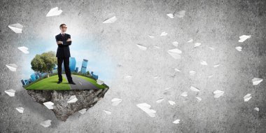 Yeşil yüzen adada beton zemine karşı duran kendine güvenen zarif iş adamı.