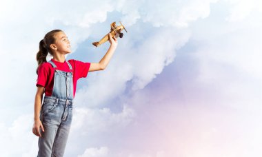 Elinde retro uçak modeliyle tulumlu şirin bir kız çocuğu.