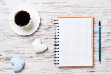 Kahve fincanı not defteri kalem ve ahşap yüzeyde iki kalp