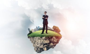 Mavi gök yeşil yüzen ada üzerinde duran zarif emin iş adamı