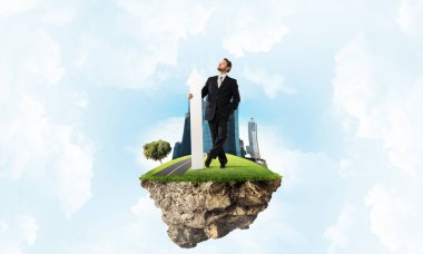 Kendinden emin ve başarılı işadamı siyah elbiseli Adası ve bulutlu gökyüzü arka plan üzerinde uçan üzerinde dururken onun elinde büyük beyaz ok ile ters işaret.