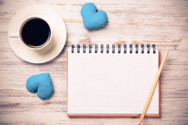 Kahve fincanı not defteri kalem ve ahşap yüzeyde iki kalp